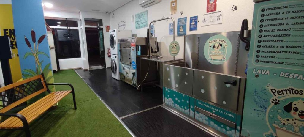 Interior del local de Perritos Limpitos en Ciudad Real con máquinas de autolavado manual y automático, lavadora para ropa de perros, mandiles, chuches y máquina de vending.
